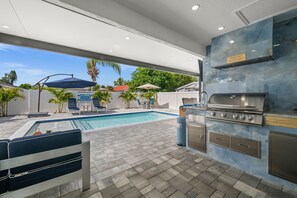 Ein Außenpoolbereich mit Grillstation und Sitzgelegenheiten.