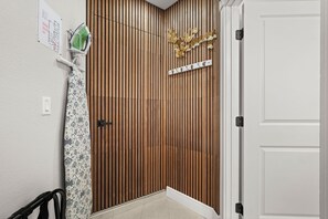 A corner of a room with a wooden slat wall, a white door, and a wall-mounted emergency evacuation plan sign. - Modern 5BR / Heated Saltwater Pool /Near Anna Maria Island/Sleeps 11 (Bradenton)
