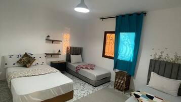 Une chambre avec deux lits, un canapé, une petite table et une table de chevet.