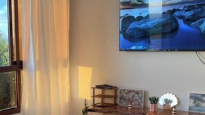 Olohuone, jossa on marmorilattia, sohva, sohvapöytä, seinälle asennettu televisio ja ikkuna, jossa on verhot.