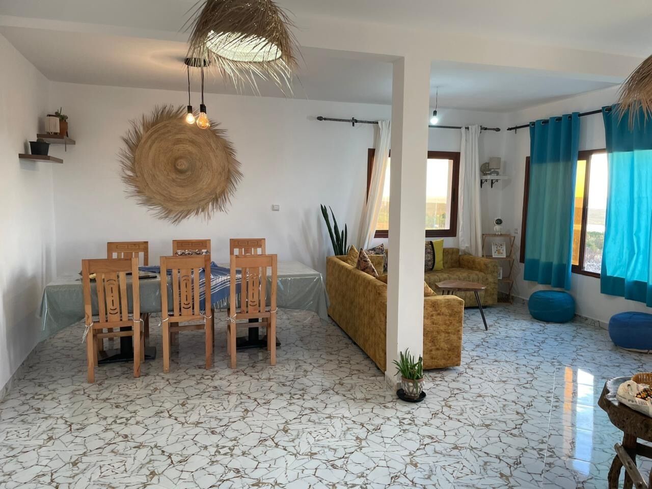 Ein Wohnzimmer mit Essbereich, einer Couch, einem Couchtisch und einer Pendelleuchte.