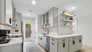 Cocina moderna con armarios blancos, horno empotrado y pileta de acero inoxidable.