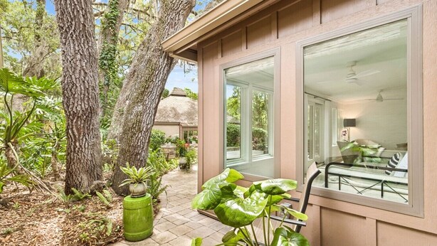 Una casa con patio, ventanas amplias y vista al jardín trasero.