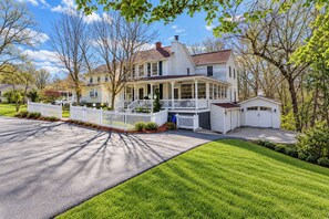 A two-story house with a front porch, a garage, and a well-maintained lawn.