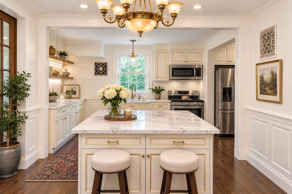 A spacious kitchen with a large island, stainless steel appliances, and a chandelier.