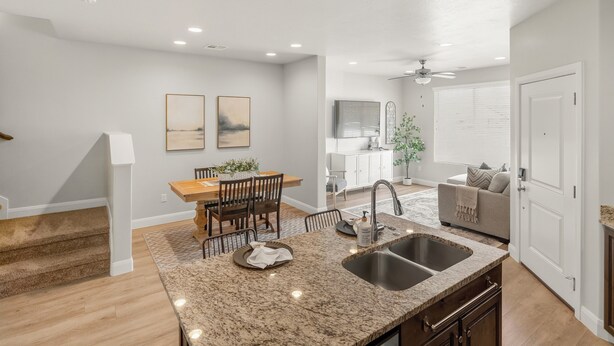 A modern kitchen with granite countertops, a sink, and a dining area with a wooden table and chairs. - Family Friendly Poolside Home near Zion & Sand Hollow (Washington)
