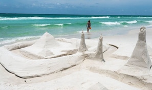 A sandy beach with a person walking towards the ocean. - Starfish ! New. Pool. Beach. Golf Cart. Sleeps 26! (Santa Rosa Beach)