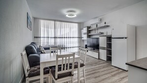 Una cocina moderna con armarios blancos, horno empotrado y refrigerador.