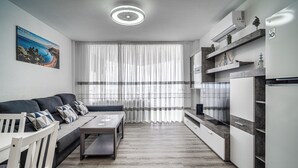 Una cocina moderna con horno integrado, un comedor con mesa y sillas, y un amplio ventanal con cortinas ligeras.