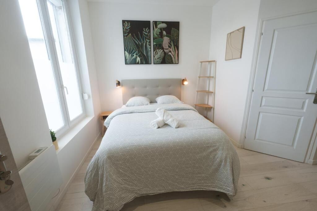 A bedroom with a bed, two bedside tables, a window, a door, and wall art.