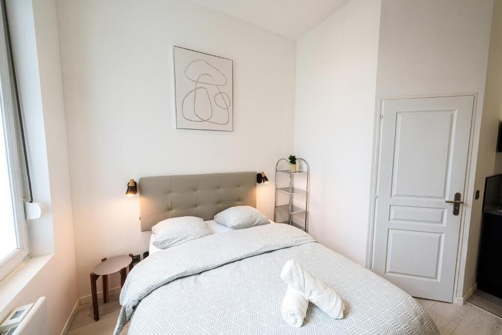 Ein Schlafzimmer mit Bett, Nachttisch, Lampe und Tür.