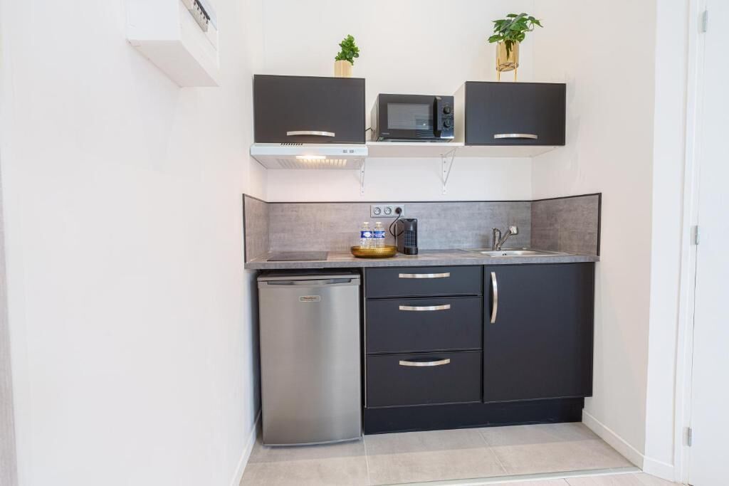 A compact kitchen with a dishwasher, dark cabinets, a microwave, and a small countertop.