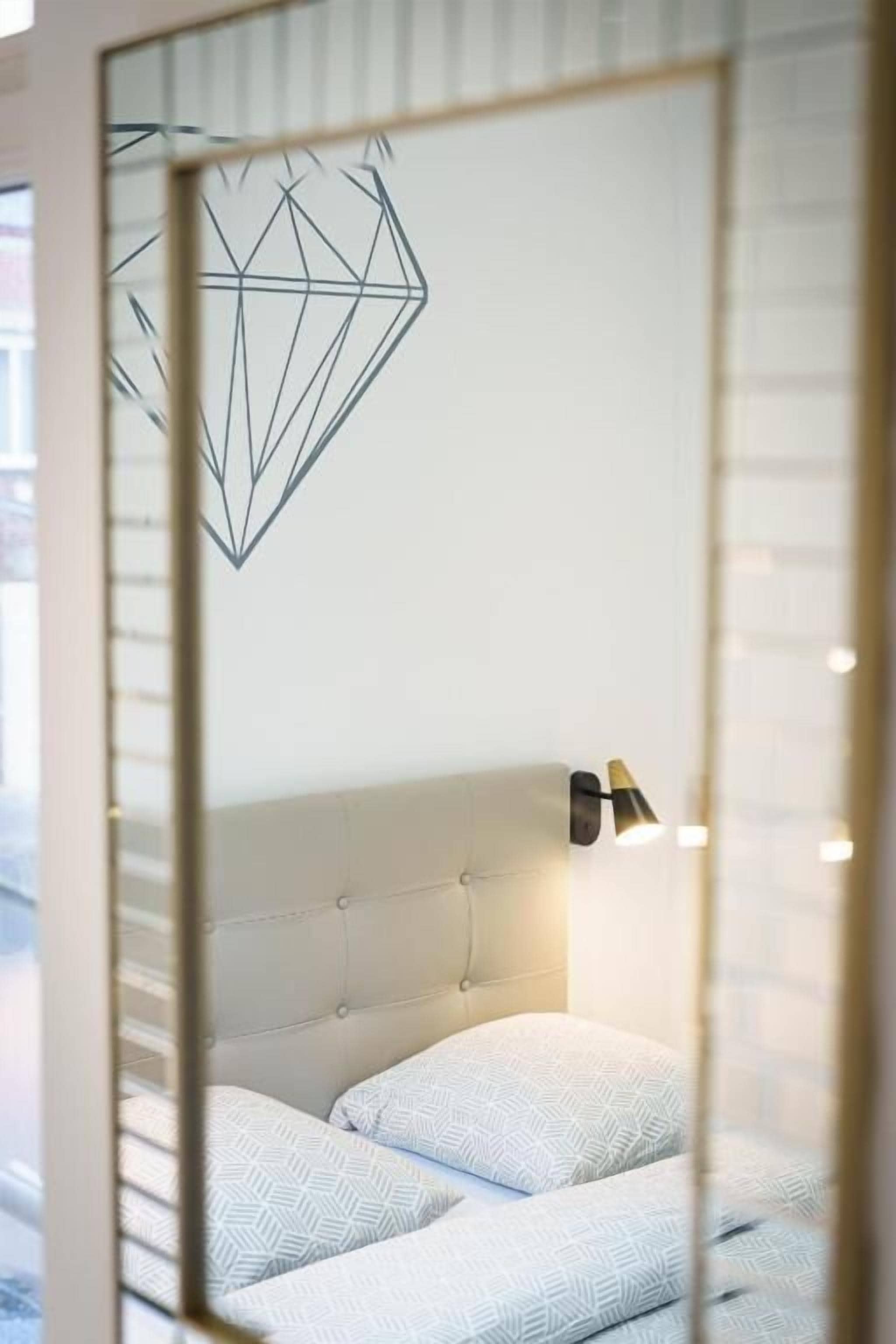 A bedroom with a bed, a headboard, and a wall-mounted light fixture.