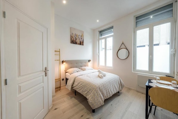 A bedroom with a bed, bedside table, and a window.