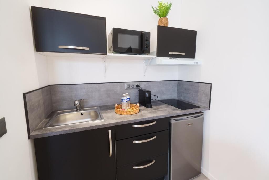 Een kleine keuken met een spoelbak, magnetron en een koelkast.