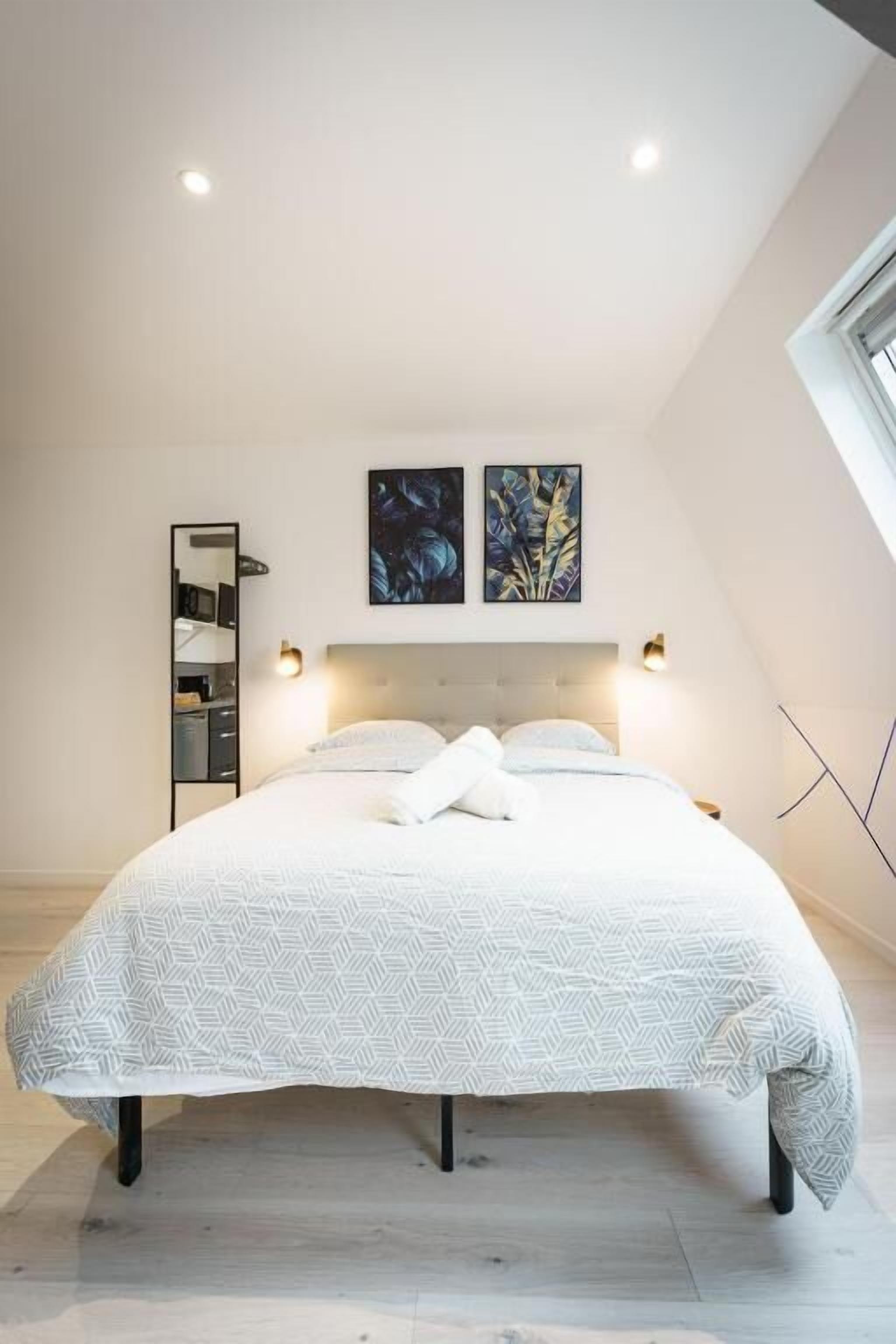 A bedroom with a bed, bedside tables, a headboard, and wall-mounted artwork.