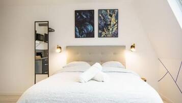 A bedroom with a bed, bedside tables, a headboard, and wall-mounted artwork.