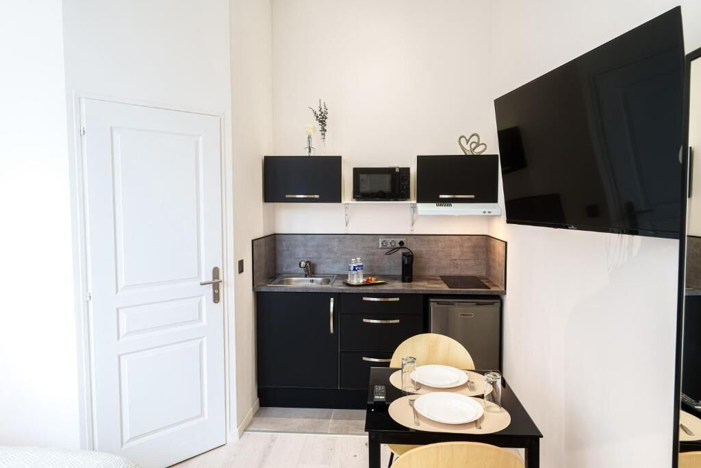 A compact kitchen with black cabinets, a microwave, a coffee maker, and a dining table set for two.