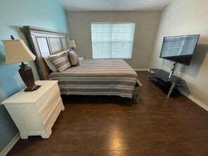 A bedroom with a bed, nightstand, lamp, TV, and window blinds. - A gateway close to Disney (Kissimmee)