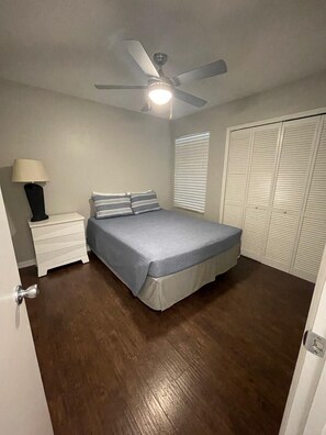 A bedroom with a bed, a nightstand, a ceiling fan, and a closet. - A gateway close to Disney (Kissimmee)