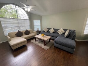 A living room with a beige sofa, a gray sectional, a wooden coffee table, and a ceiling fan. - A gateway close to Disney (Kissimmee)