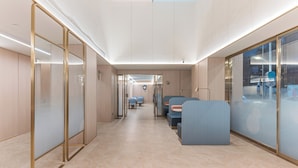 A modern interior with glass partitions, a central seating area, and a view through the glass.