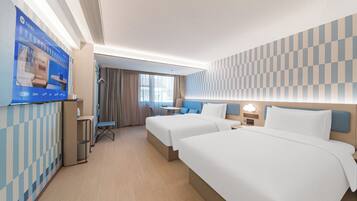 Habitación de hotel con dos camas, televisión, escritorio y baño.