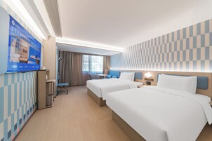 Habitación de hotel con dos camas, televisión, escritorio y baño.