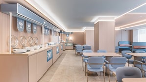 A modern hotel lobby with a long reception desk, seating area, and a view of the city.