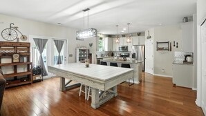 A spacious kitchen with a central island, wooden flooring, and pendant lighting. - Low country luxury near Palmetto Bluff (Bluffton)