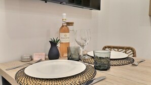 Uma mesa de jantar posta com um prato branco, talheres, uma garrafa de vinho e copos.