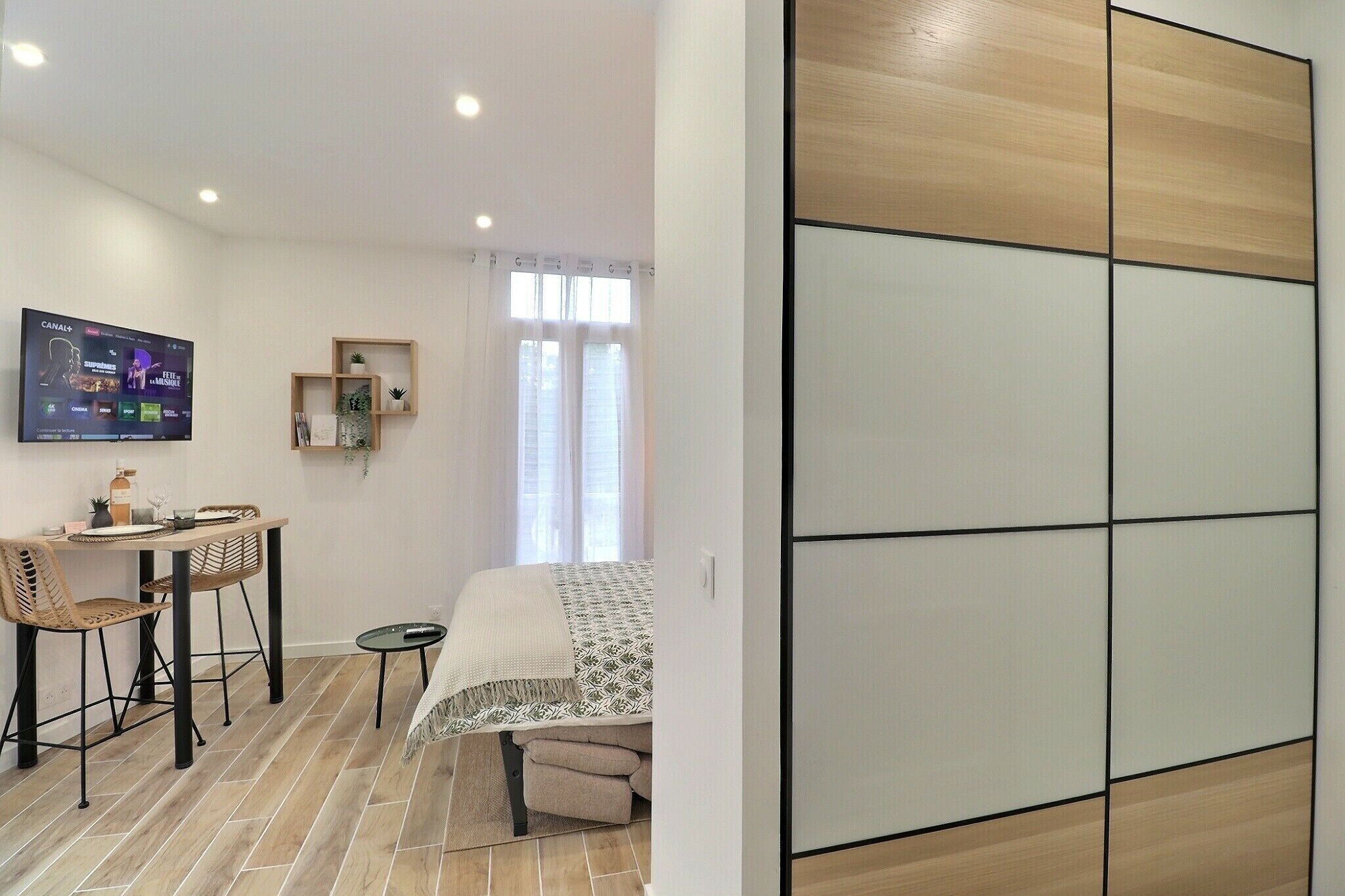 Une chambre moderne équipée d’un lit, d’un bureau avec des chaises, d’une télévision et d’une porte coulissante.