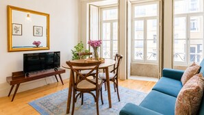 Un soggiorno con televisione, mobili in legno, un divano e ampie finestre.