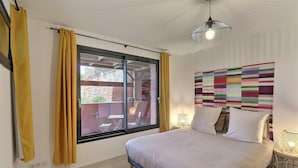 A bedroom with a bed, curtains, a window, a wall art piece, and a hanging light fixture. - Villa des Pins (Ventabren)