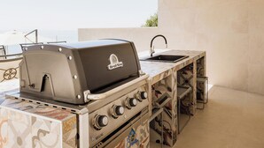 An outdoor kitchen with a Broil King grill, a sink, and a tiled backsplash. - Luxury Villa for 14 with 2 Pools, Sauna & Sea View (Ičići)