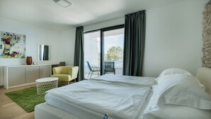 A modern hotel room with a bed, a desk, a chair, and a view of the outdoors. - Luxury Villa for 14 with 2 Pools, Sauna & Sea View (Ičići)