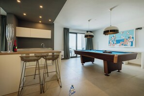 A modern kitchen with a pool table, bar stools, and a painting on the wall. - Luxury Villa for 14 with 2 Pools, Sauna & Sea View (Ičići)