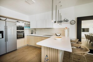 Een moderne keuken met een centraal eiland, roestvrijstalen apparatuur en een houten vloer.
