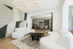 A modern living room with a sofa, a coffee table, and a dining area with a table and chairs. - Luxury Villa for 14 with 2 Pools, Sauna & Sea View (Ičići)