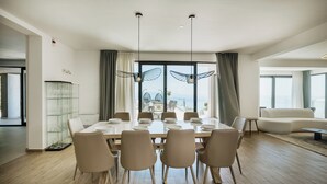 A dining area with a large table, chairs, and a view of the sea. - Luxury Villa for 14 with 2 Pools, Sauna & Sea View (Ičići)
