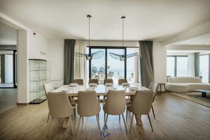 A dining area with a large table, chairs, and a view of the sea. - Luxury Villa for 14 with 2 Pools, Sauna & Sea View (Ičići)