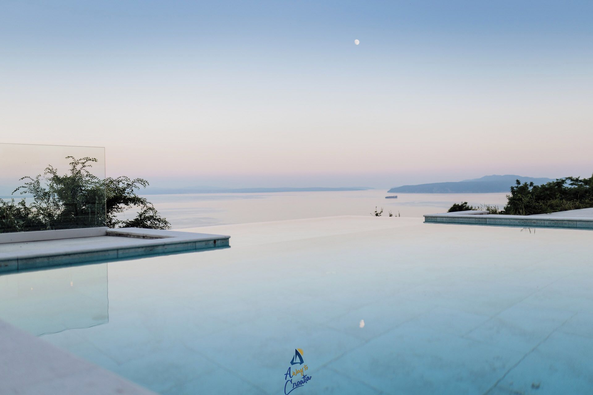 Une piscine offrant une vue dégagée sur la mer et les montagnes lointaines.