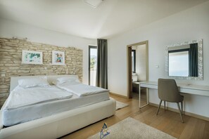 Een slaapkamer met een bed, een bureau en een stoel. Er is een stenen muur en een raam met gordijnen.