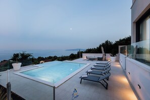 A rooftop pool with lounge chairs, a glass balustrade, and a view of the sea. - Luxury Villa for 14 with 2 Pools, Sauna & Sea View (Ičići)