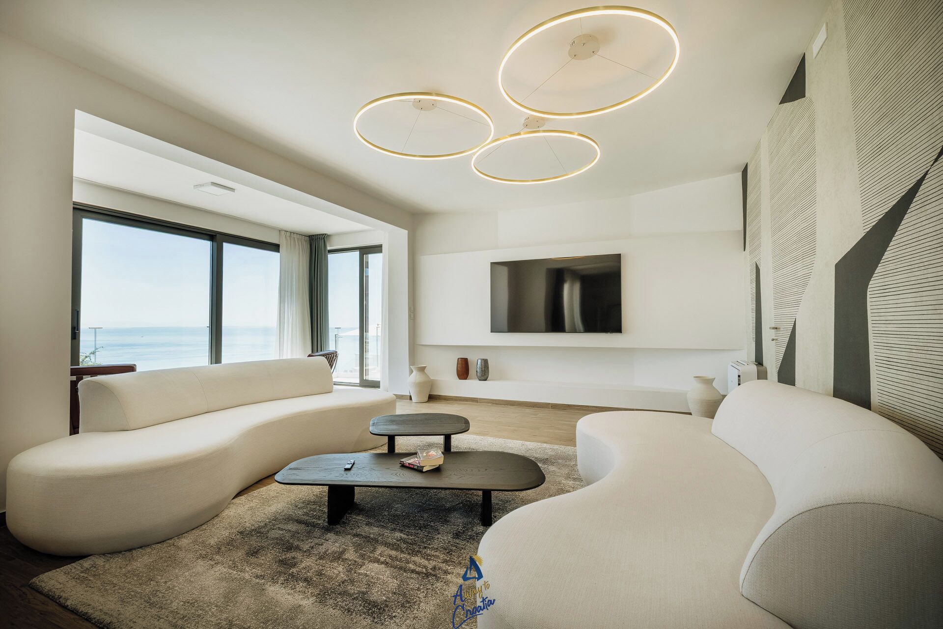 Un soggiorno moderno con una grande finestra, una TV a schermo piatto e un originale lampadario.