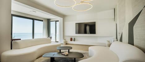 A modern living room with a large window, a flat-screen TV, and a unique ceiling light fixture.