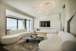 A modern living room with a large window, a flat-screen TV, and a unique ceiling light fixture. - Luxury Villa for 14 with 2 Pools, Sauna & Sea View (Ičići)