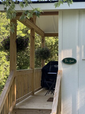 Una terraza de madera con un pérgola, una parrilla y un letrero que dice 'The Nook'.