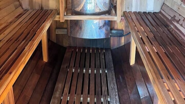 Eine Sauna mit Holzbänken und einer zentralen Heizvorrichtung.