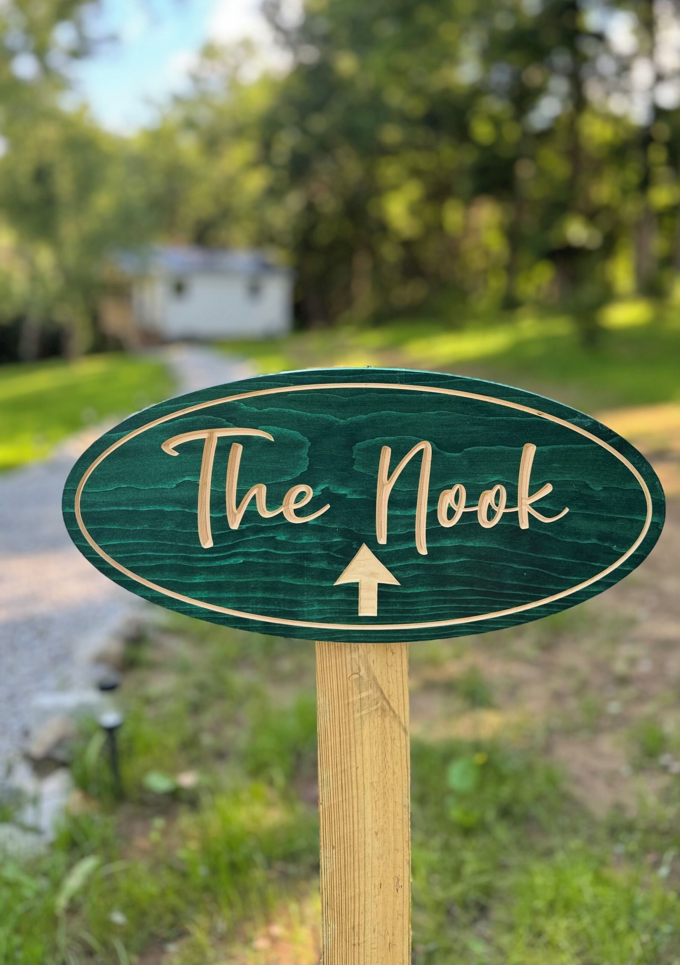 A wooden sign with the text 'The Nook' and an arrow pointing upwards, indicating a direction or location.